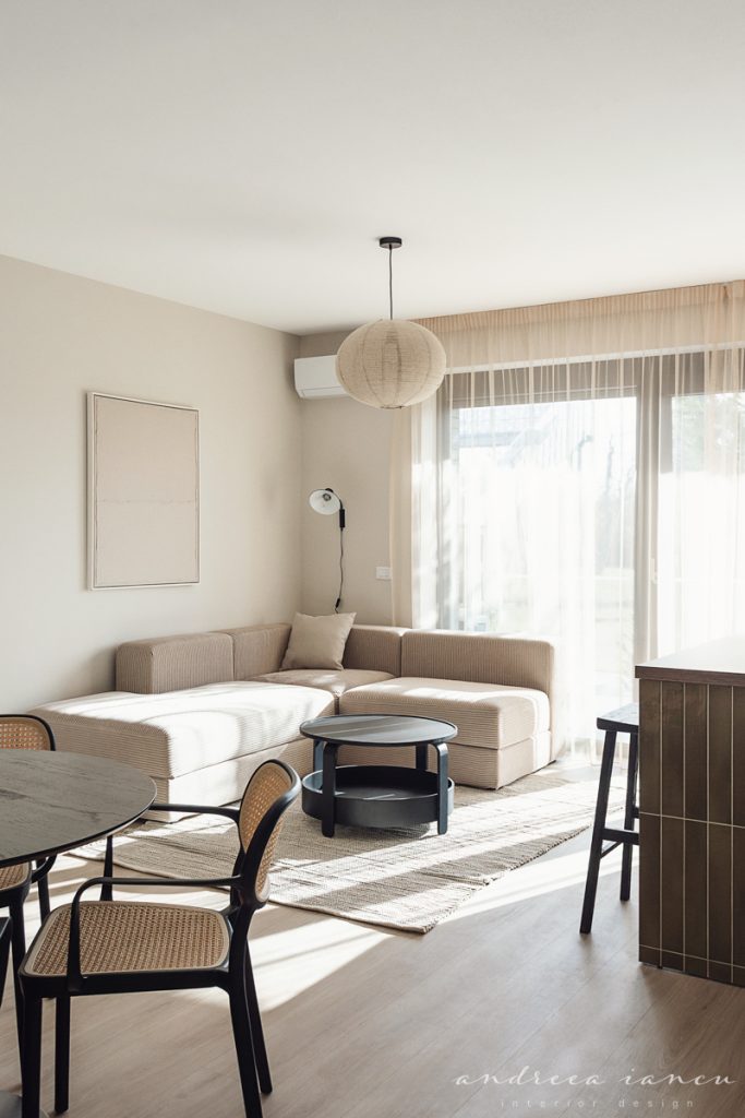 Living room view of small apartment interior design with dark wood and moss green tiles.
