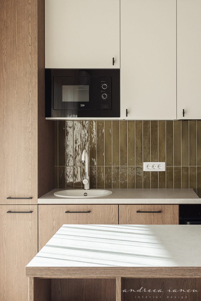 Kitchen view of small apartment interior design with dark wood and moss green tiles.